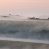 A wave of morning mist passes over a ridge line on the South Downs, Sussex