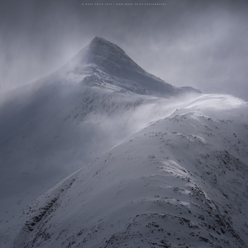 High winds throw spindrift around high up on a Scottish mountain peak