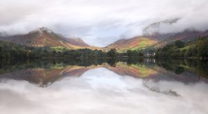 Perfect reflections across a Lake District lake as the light hits the landscape