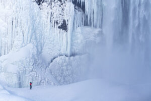 An enthusiastic photographer dwarfed by the might of an Icelandic waterfall..