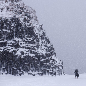 Basalt rocks and a human beseiged by a snowstorm.