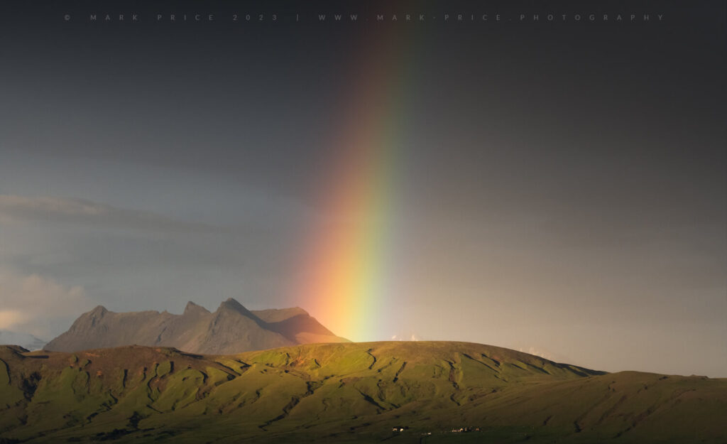 A beautiful rainbow forms in the Midnight Sun season, Iceland - the scale of the bow, and landscape highlighted by the farm to bottom of image